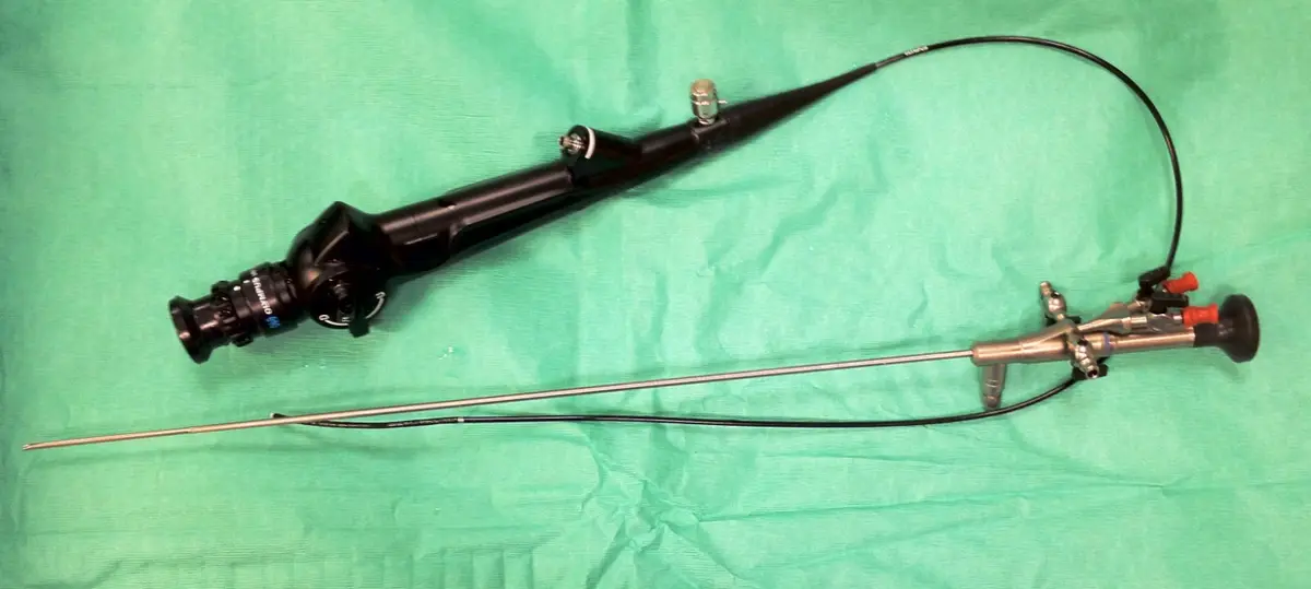 A flexible ureteroscope lying on a green surgical drape, with its handle and long thin flexible shaft.
