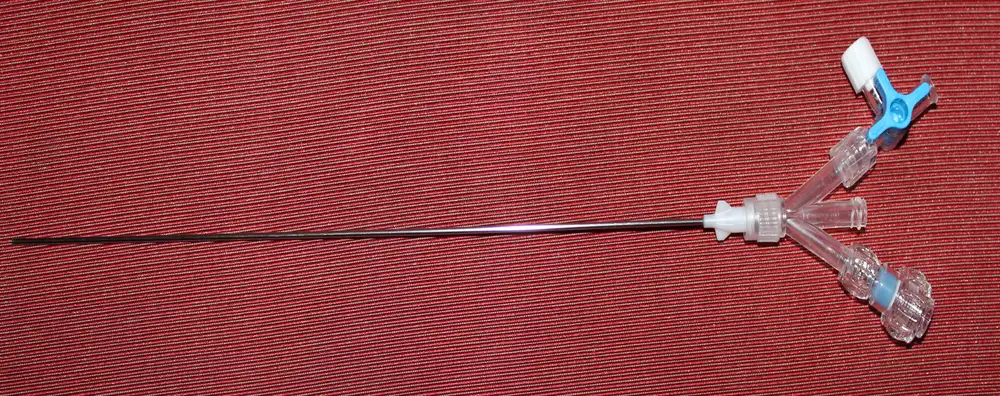 Photograph of the assembled micro PCNL working shaft with its three-port adapter, laid on a red cloth.
